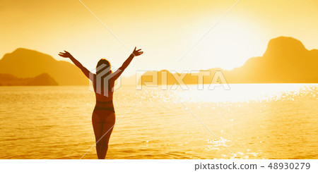 Freedom and happiness woman on beach. She is enjoying serene ocean nature during travel holidays Freedom and happiness woman on beach. She is enjoying serene ocean nature during travel holidays 48930279