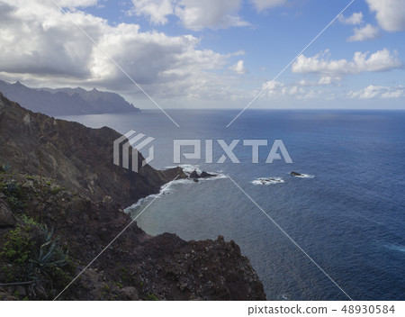 view on high hills and rocky cliffs in the atlantic ocean, sea dramatic blue sky with white clouds view on high hills and rocky cliffs in the atlantic ocean, sea dramatic blue sky with white clouds 48930584