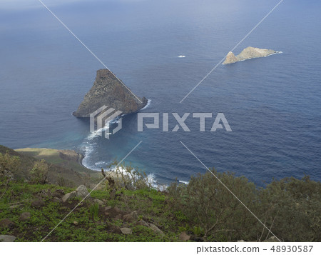 view on rock in the sea El Draguillo with green hills and dramatic blue sky white clouds in anaga view on rock in the sea El Draguillo with green hills and dramatic blue sky white clouds in anaga 48930587