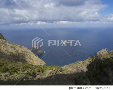 view on rock in the sea El Draguillo with green hills and dramatic blue sky white clouds in anaga view on rock in the sea El Draguillo with green hills and dramatic blue sky white clouds in anaga 48930837