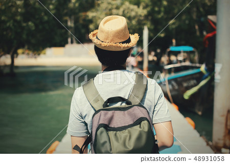 Back of young male solo traveler walking on path towards tropical island in Thailand 48931058
