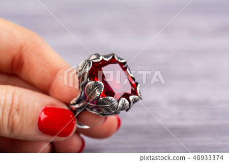 A stone from ruby quartz with a facet in a ring A stone from ruby quartz with a facet in a ring 48933374