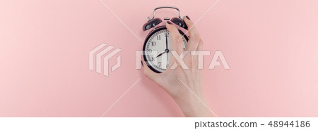 Female hand with alarm clock. Morning concept Female hand with alarm clock. Morning concept 48944186