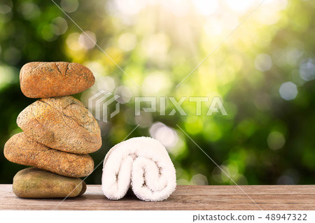 Stack of stone and white towel on wooden floor on 48947322