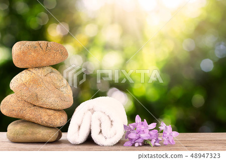Stack of stone and white towel with flower on 48947323
