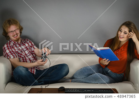 Woman playing games man reading book 48947365