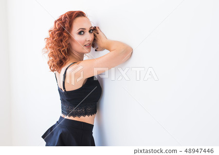 People and fashion concept - Redhead woman in black shirt and skirt posing isolated on white 48947446