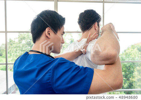 Physical therapist stretching athlete male patient 48948680