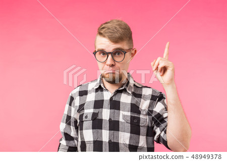 Attractive funny young man wearing eyeglasses and plaid shirt pointing up with his finger isolated Attractive funny young man wearing eyeglasses and plaid shirt pointing up with his finger isolated 48949378