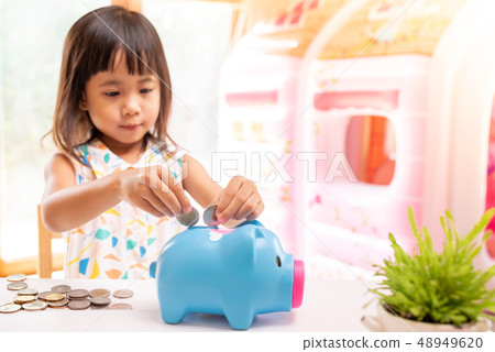 Asian girl putting coin in the piggy bank Asian girl putting coin in the piggy bank 48949620