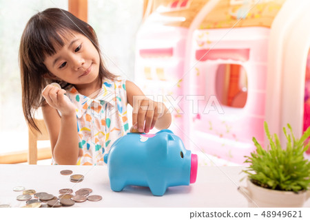 Asian girl putting coin in the piggy bank Asian girl putting coin in the piggy bank 48949621