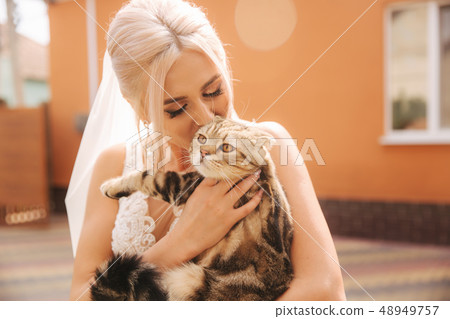 Beautiful blond hair bride with her pet. Cat on brides hands Beautiful blond hair bride with her pet. Cat on brides hands 48949757