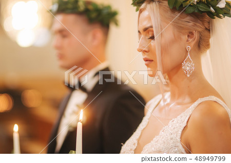 Beautiful couple in church. Newlyweds swear to each other to love forever. Happy bride and groom Beautiful couple in church. Newlyweds swear to each other to love forever. Happy bride and groom 48949799