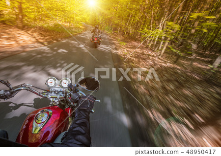 Motorcycle driver riding in spring forest. Motorcycle driver riding in spring forest. 48950417
