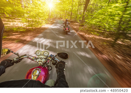Motorcycle driver riding in spring forest. Motorcycle driver riding in spring forest. 48950420