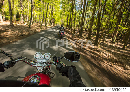 Motorcycle driver riding in spring forest. Motorcycle driver riding in spring forest. 48950421