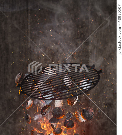 Kettle grill with hot briquettes and cost iron grid flying in the air. Kettle grill with hot briquettes and cost iron grid flying in the air. 48950507