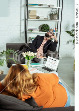 Concentrated brunette therapist sitting opposite his client Concentrated brunette therapist sitting opposite his client 48950697