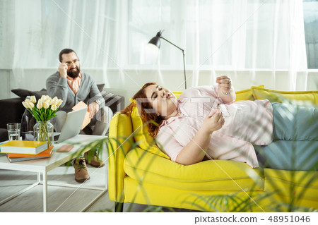 Relaxed overweight young woman lying on sofa 48951046