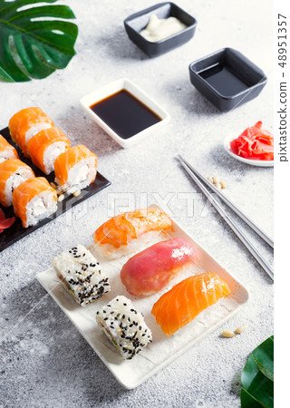 Various sushi on ceramic plate with metal Korean sticks on light stone background with green leaves 48951357