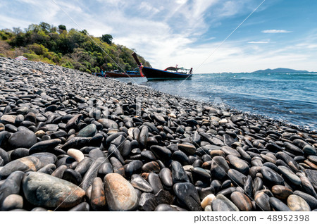 Black stone island with wooden boat on coastline Black stone island with wooden boat on coastline 48952398
