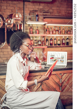 Profile shot of African-American bar employee looking at tablet 48952532