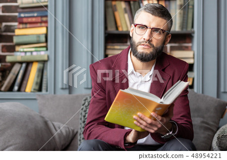 Dark-eyed bearded man feeling inspired after reading interesting book 48954221