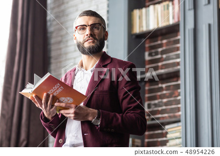 Handsome dark-eyed man feeling excited after reading interesting book 48954226