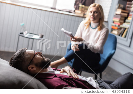 Bearded businessman lying on sofa while having psychological therapy Bearded businessman lying on sofa while having psychological therapy 48954318