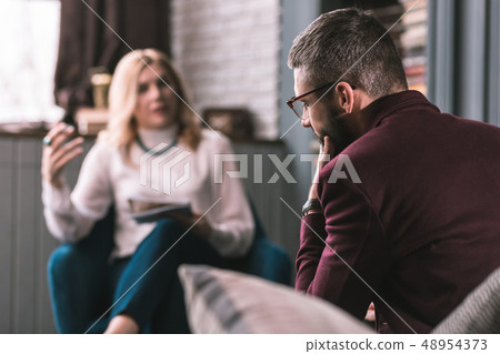 Bearded man wearing glasses feeling concerned visiting therapist 48954373