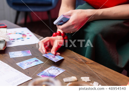 Top view of woman wearing red bracelet reading oracle cards 48954540