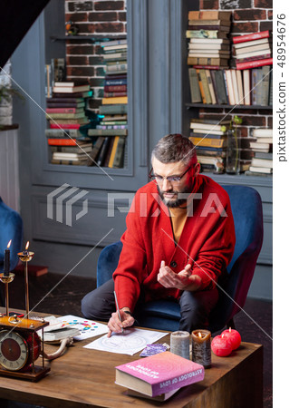 Astrologist sitting at the table with candles studying new practice Astrologist sitting at the table with candles studying new practice 48954676