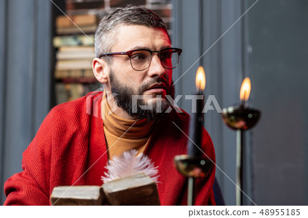 Bearded diviner feeling thoughtful after reading ancient magician book 48955185