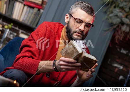 Bearded mature diviner wearing bracelet holding little old magician book 48955220