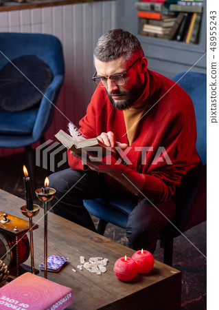 Fortune-teller wearing glasses reading old magic book about oracle cards Fortune-teller wearing glasses reading old magic book about oracle cards 48955243