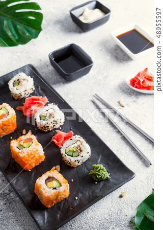 Various Fresh and delicious sushi set on black and white slate with metal and slate sticks, sauce 48955597