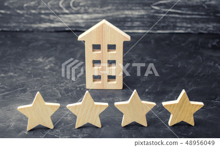 Wooden house and four stars on a gray background. Wooden house and four stars on a gray background. 48956049