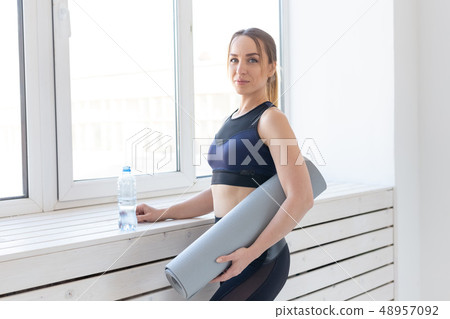 People, sport and fitness concept - young woman with yoga mat and bottle of water standing near People, sport and fitness concept - young woman with yoga mat and bottle of water standing near 48957092
