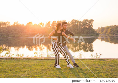 Kizomba, bachata, zouk and latin social dance concept - Man and woman dancing over nature background Kizomba, bachata, zouk and latin social dance concept - Man and woman dancing over nature background 48958059