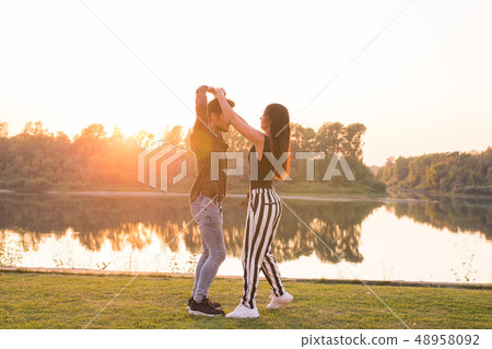 Romantic, social dance and people concept - young couple dancing bachata on the background of sunset Romantic, social dance and people concept - young couple dancing bachata on the background of sunset 48958092