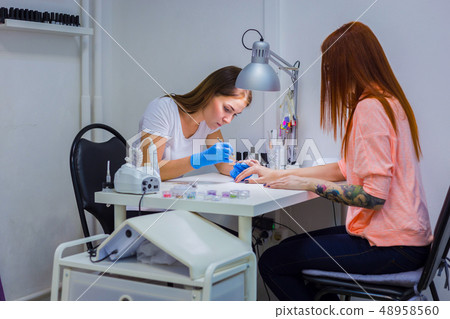 Manicurist treating client at beauty salon - painting on the nai 48958560