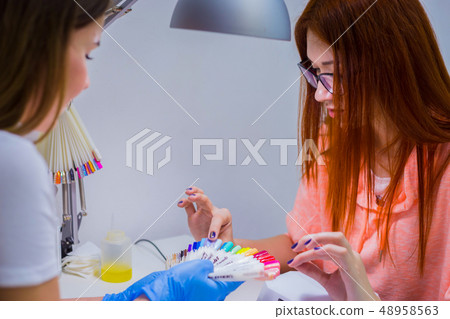 Nail technician shows the color palette of nail services in beau 48958563