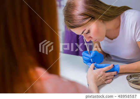 Professional beautician applying nail polish to female nail Professional beautician applying nail polish to female nail 48958587