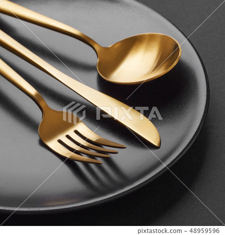 Gold cutlery set on black background Gold cutlery set on black background 48959596