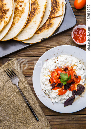 Quesadilla, salad with cottage cheese and tomatoes on wood table. 48961962