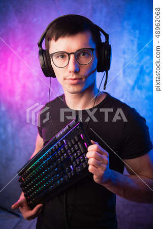 Computer nerd with keyboard over colorful pink and blue neon lit wall Computer nerd with keyboard over colorful pink and blue neon lit wall 48962068
