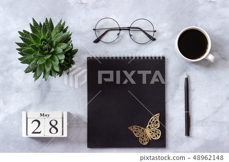 Office or home table desk. Wooden cubes calendar May 28. Black notepad, cup of coffee, succulent Office or home table desk. Wooden cubes calendar May 28. Black notepad, cup of coffee, succulent 48962148