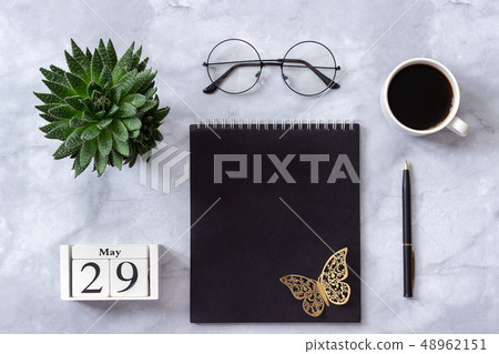 Office or home table desk. Wooden cubes calendar May 29. Black notepad, cup of coffee, succulent Office or home table desk. Wooden cubes calendar May 29. Black notepad, cup of coffee, succulent 48962151