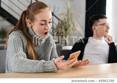 Woman reading her man's cheating messages on his phone Woman reading her man's cheating messages on his phone 48962190