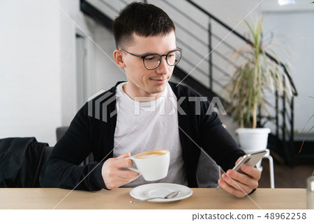 Handsome man having coffee and using smartphone at coffee shop 48962258